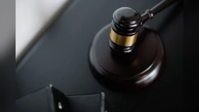 From above of wooden gavel on round surface near folders on table in courtroom
